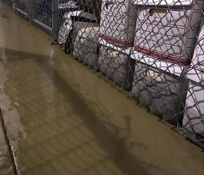 boxes of documents behind chain link fence with water on concrete floor