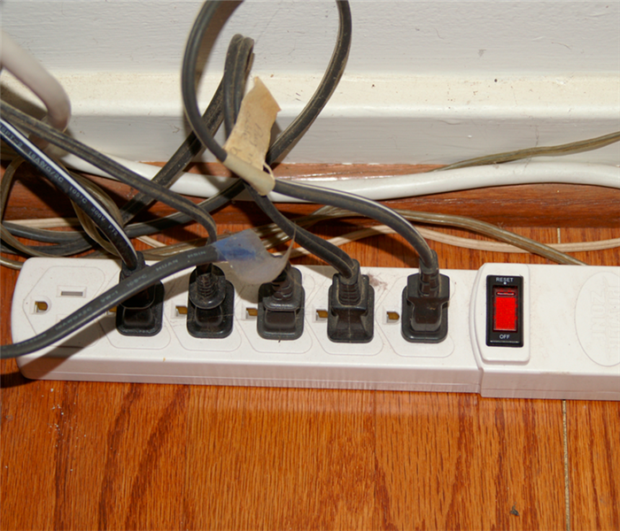 power strip on hardwood floor with multiple plugs plugged into it